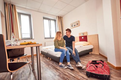 a man and woman sitting on a bed in a room at DJH-Gästehaus Bermuda3Eck in Bochum