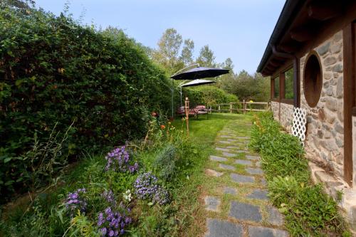 a garden with a patio with an umbrella and flowers at La Tronera del Bierzo Restaurante-Hotel in Villadepalos