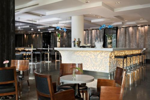 a restaurant with a bar with wooden chairs and tables at Hotel Puerta America in Madrid