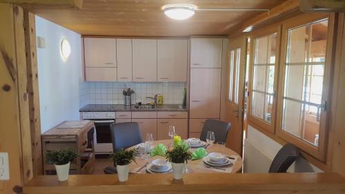 a kitchen with a table with chairs and a dining room at Holzhaus bei Interlaken in Goldswil