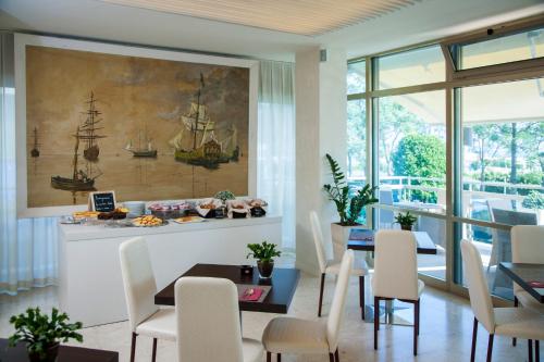 a dining room with a painting of a ship on the wall at Hotel Mon Cheri in Riccione