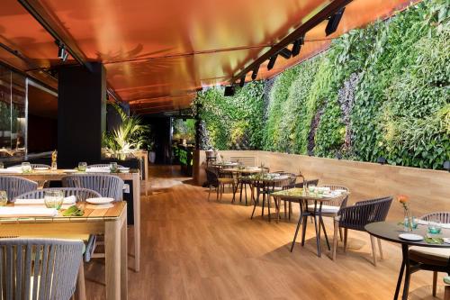 a restaurant with tables and chairs and a green wall at Hotel Puerta America in Madrid