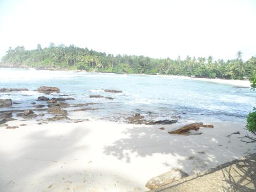 a view of a beach with rocks in the water at Gold ocean house in Hiriketiya
