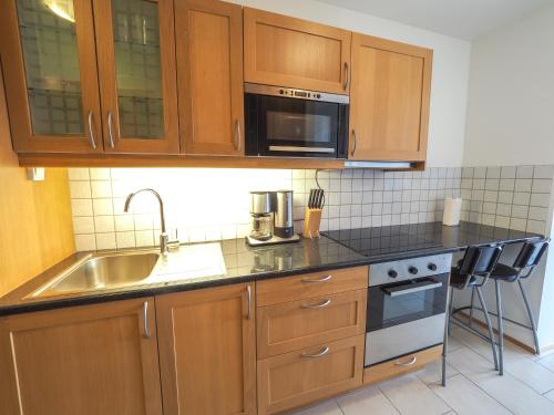 a kitchen with wooden cabinets and a sink and a microwave at Hotel Laxarbakki in Hvalfjarðarsveit