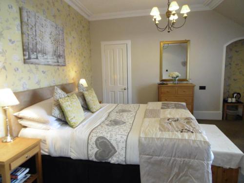 a bedroom with a bed and a dresser and a mirror at Moyness House in Inverness