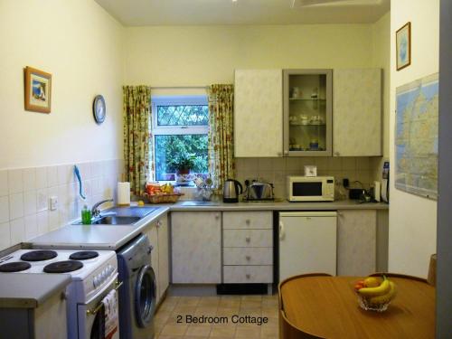 a kitchen with a sink and a stove and a table at Hallmount Cottage - Belfast in Belfast
