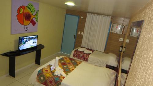 a room with two beds and a television in it at Beira Mar Porto de Galinhas Hotel in Porto De Galinhas