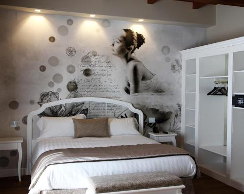 a bedroom with a white bed and a wall with a mural at Suites & Apartments Liola' in Castrocielo