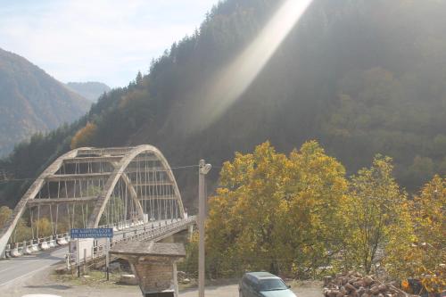 a bridge over a road with a mountain in the background at Hotel Restaurant Kakhaberi in Bibiliani