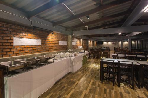 a restaurant with white tables and chairs and brick walls at City Hotel Krabi in Krabi town