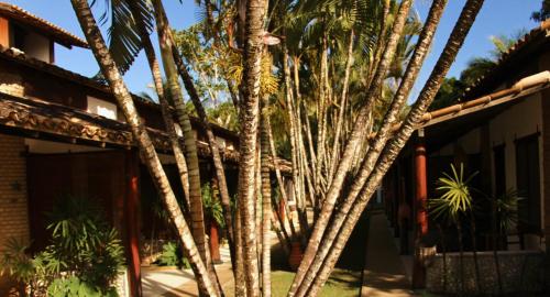 a group of palm trees in front of a building at Pousada El Capitan in Barra Grande