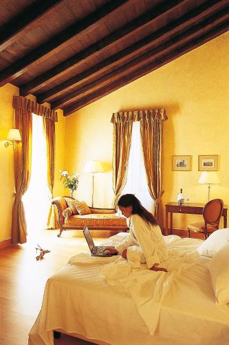 a woman sitting on a bed using a laptop at Siora Vittoria Boutique Hotel in Corfu Town