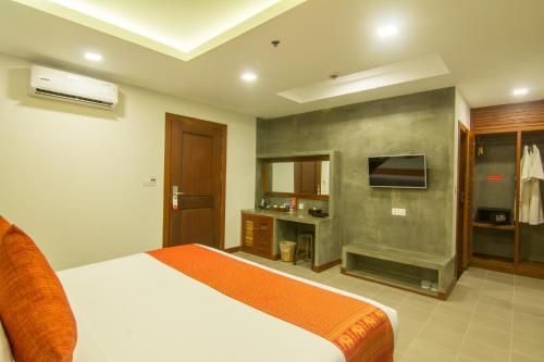 1 dormitorio con 1 cama y TV. en Chhay Long Angkor Boutique Hotel Siem Reap, en Siem Reap