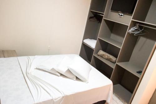 a room with a bed with a white table and shelves at Colonial Hotel Itatiba in Itatiba