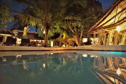 uma piscina em frente a um edifício com palmeiras em Miti Miwiri em Ibo