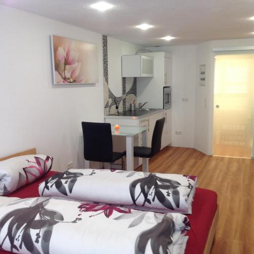 a room with two beds and a table and a kitchen at Ferienwohnung Sasbachwalden H15 Ap6 mit beheiztem Innenpool und Sauna in Sasbachwalden