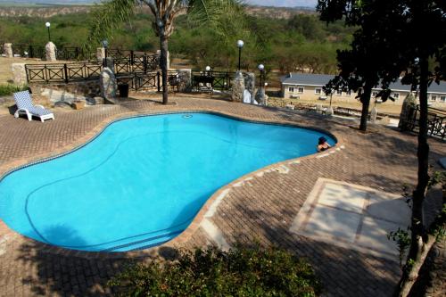 a large blue swimming pool in a yard at African Rest Lodge in Barberton