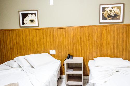 a room with two beds and a wooden wall at Colonial Hotel Itatiba in Itatiba