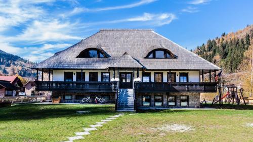 a house with a gambrel roof on a grass field at Pensiunea La Moară in Fundu Moldovei