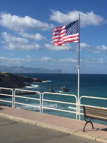 an american flag flying over the ocean next to a bench at Case Saniela in Terrasini