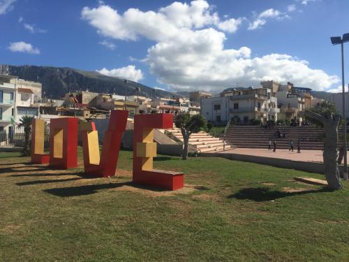 a large sculpture in a park with buildings in the background at Case Saniela in Terrasini