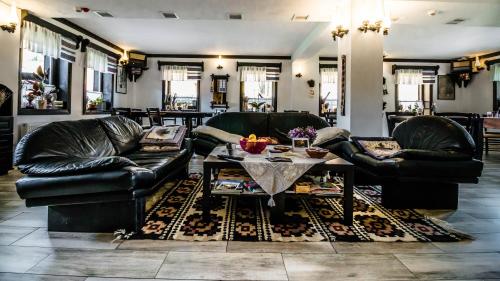 a living room with two leather couches and a table at Pensiunea La Moară in Fundu Moldovei
