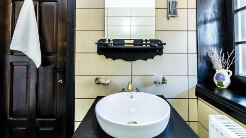 a bathroom with a large white sink on a black counter at Pensiunea La Moară in Fundu Moldovei