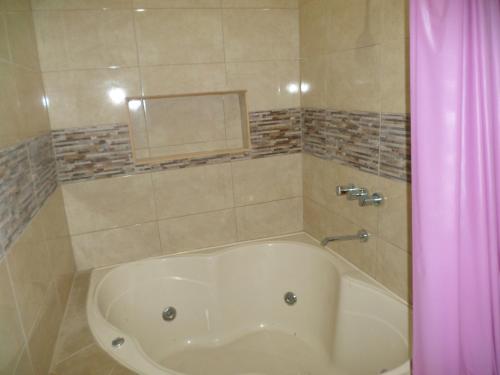 uma banheira na casa de banho com uma cortina de chuveiro rosa em D´ Barrig em Trujillo