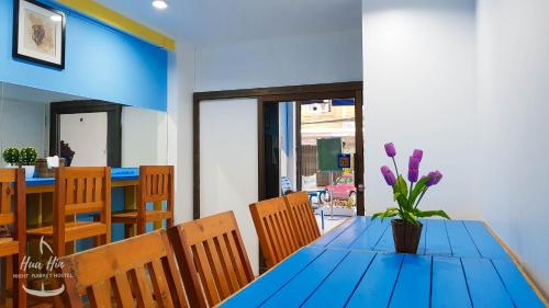 a blue table with a vase of purple flowers on it at HuaHin Night Market Hostel in Hua Hin