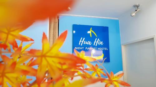 a sign in a room with flowers in the foreground at HuaHin Night Market Hostel in Hua Hin