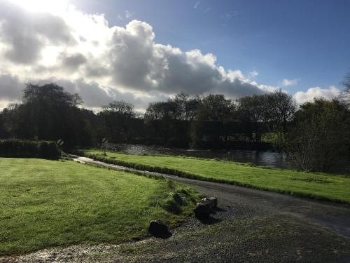 a grassy field next to a river with a road at The Cothi Bridge Apartments in Carmarthen