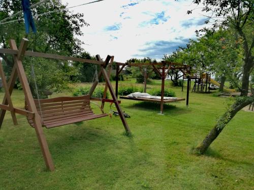 a wooden bench in a park with a bed at Agroturystyka u Karoliny in Sarbinowo