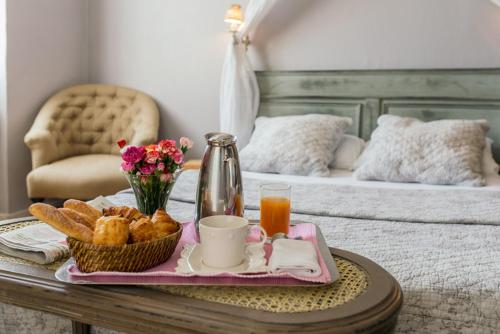 un tavolo con un vassoio di prodotti per la colazione su un letto di Hôtel du Parc a Montélimar