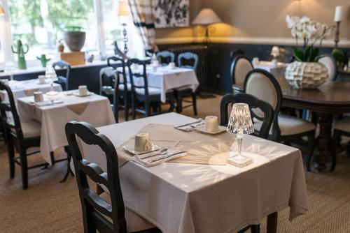 un restaurante con mesas y sillas con manteles blancos en Hôtel du Parc, en Montélimar