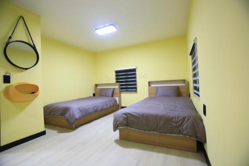 two beds in a room with yellow walls at Daegwanryeong Egg Guesthouse in Pyeongchang 
