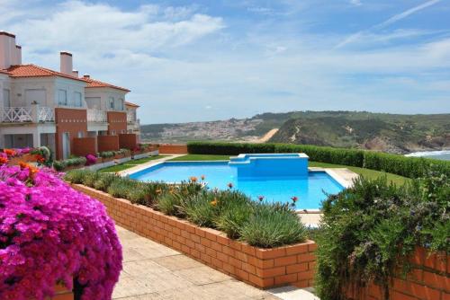 a swimming pool in a yard with flowers at Apartamento Vista Premium Sto António in São Martinho do Porto