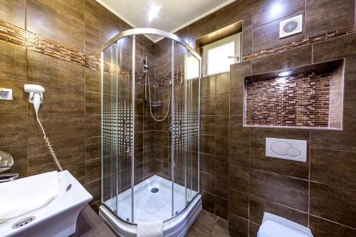 a bathroom with a shower and a toilet and a sink at Royal Apartments Hotel Kecskemét in Kecskemét