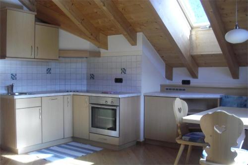 una cucina con armadi bianchi, tavolo e finestra di Residence Oberhauser a Valdaora