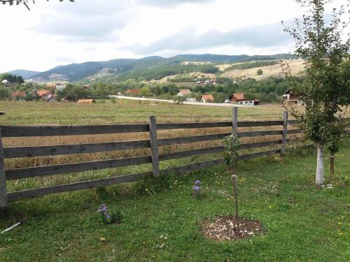 a wooden fence in a field with a tree at Holiday Home Vila Milka in Kremna