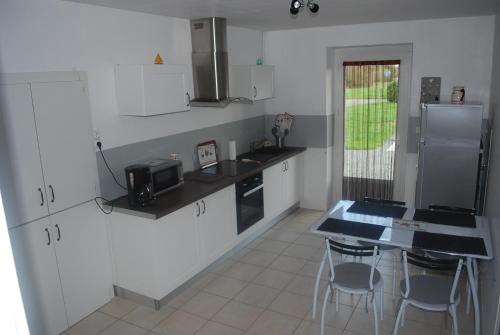 une cuisine avec des armoires blanches et un comptoir dans l'établissement La Ferme du moulin, à Montaigu-Vendée