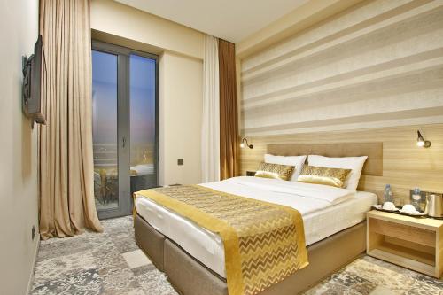 a bedroom with a large bed and a large window at Ameri Plaza Tbilisi in Tbilisi City