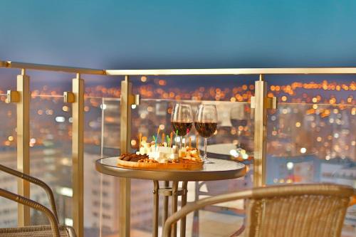 a table with two glasses of wine and a cake and candles at Ameri Plaza Tbilisi in Tbilisi City