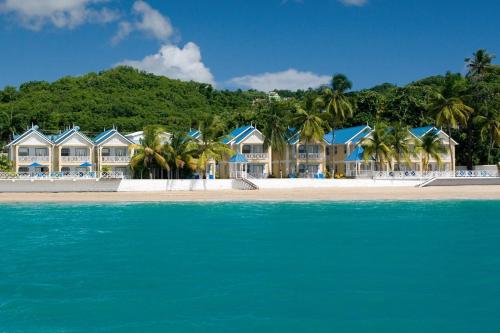 a row of houses on a beach next to the water at Villa Beach Cottages in Castries