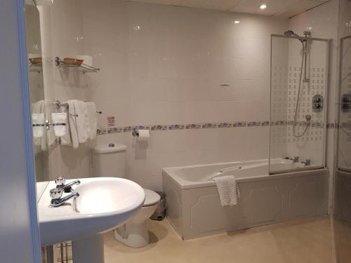a bathroom with a sink, toilet and bathtub at Burley Court Hotel in Bournemouth