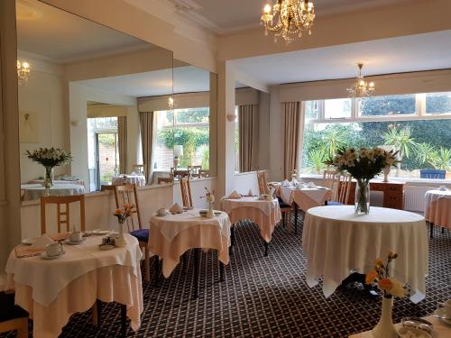 um restaurante com mesas e toalhas de mesa brancas em Burley Court Hotel em Bournemouth
