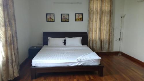 a bedroom with a large bed with white sheets at Tulip in Chennai