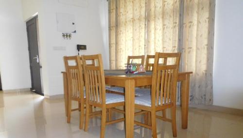 a dining room table with four chairs around it at Tulip Serviced Villa in Chennai