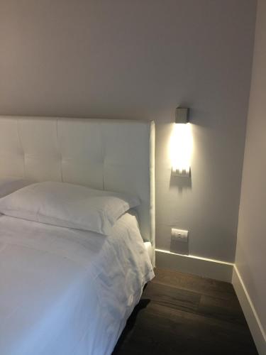 a bedroom with a white bed with a light on the wall at La Casa di Paola in Lovere