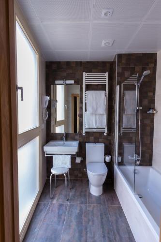 a bathroom with a toilet and a sink and a tub at Hotel Novo Cándido in Ourense