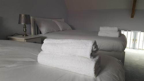 a white bed with white towels stacked on it at The George & Dragon Felton in Felton